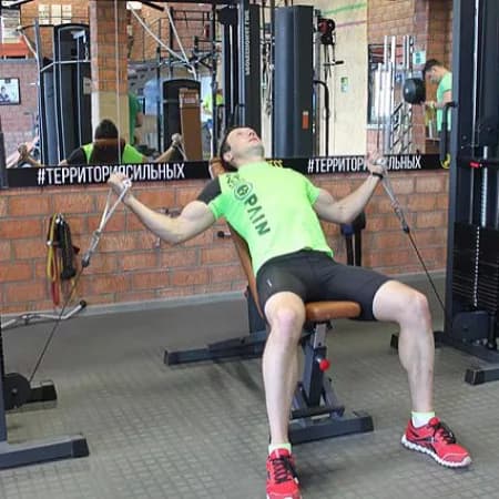 Сведения рук на нижнем блоке лежа на наклонной скамье